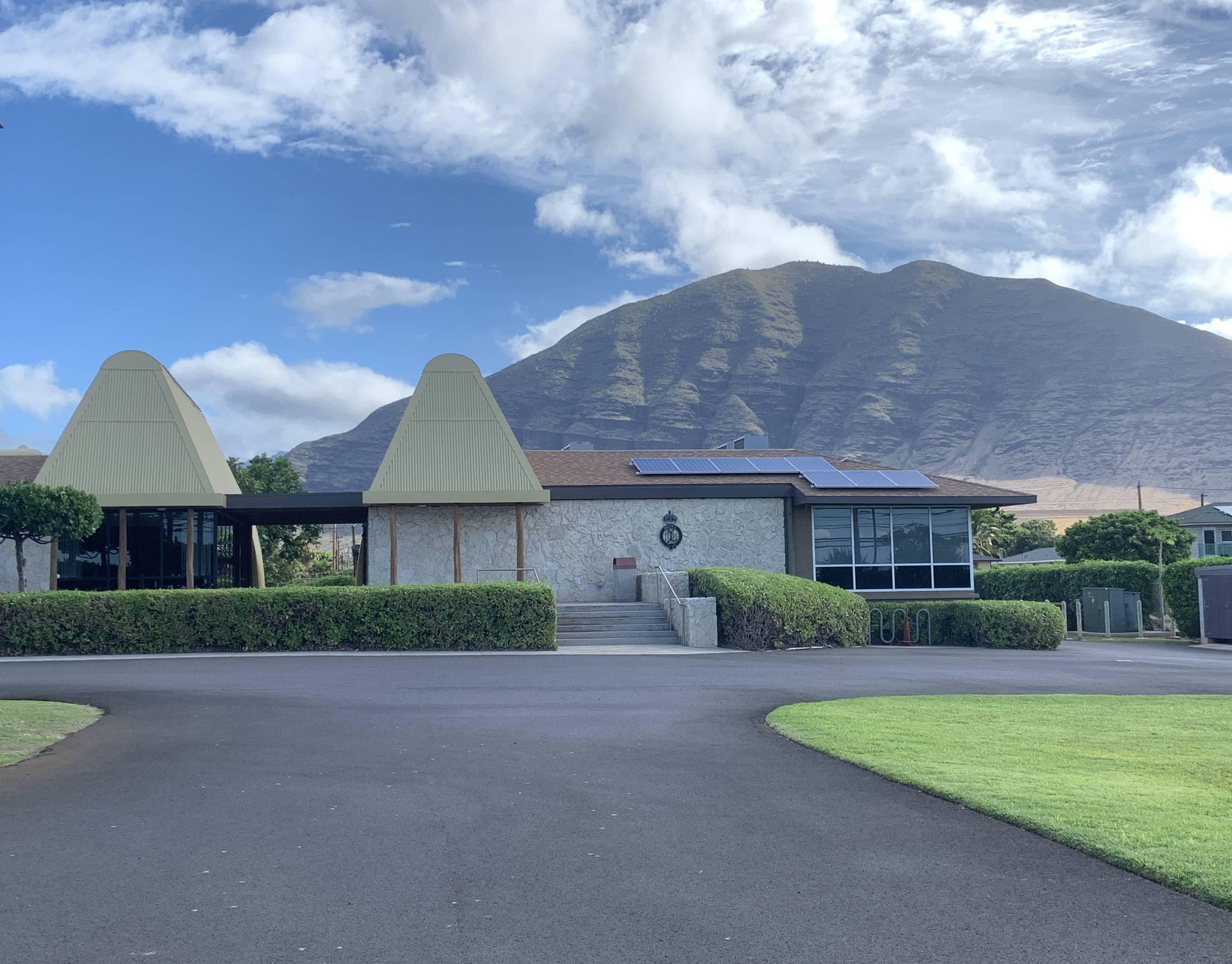 Green lawn and building in front of mountains.