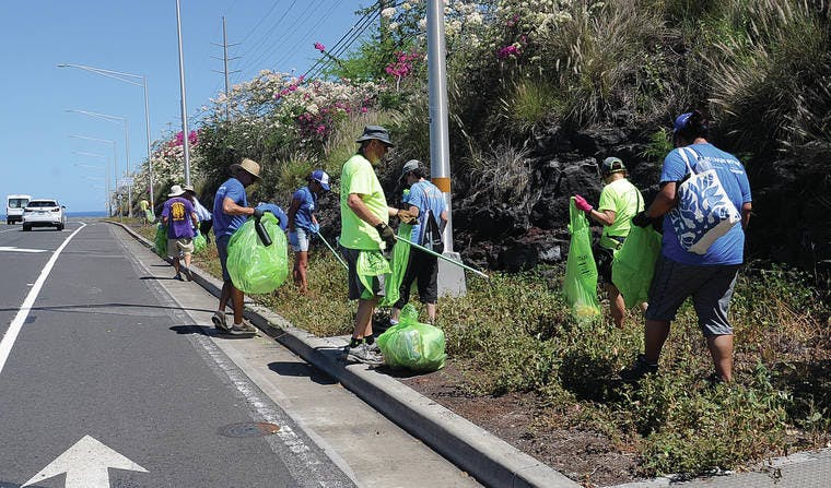Volunteers clean up trash off of Queen Kaahumanu Highway on Friday morning.