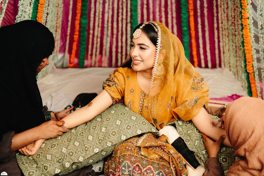 Womens putting mehndi on Muslim bride's hand captured