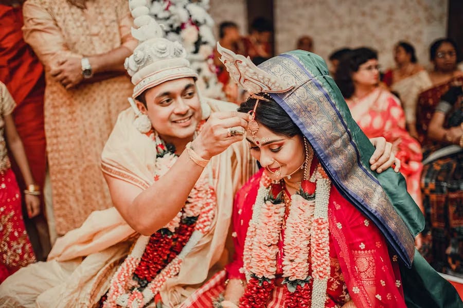 Groom putting vermillion on bride's forehead