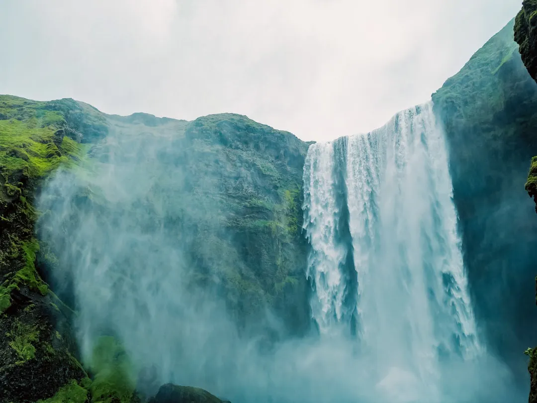 a very tall waterfall with green moss growing on it's sides