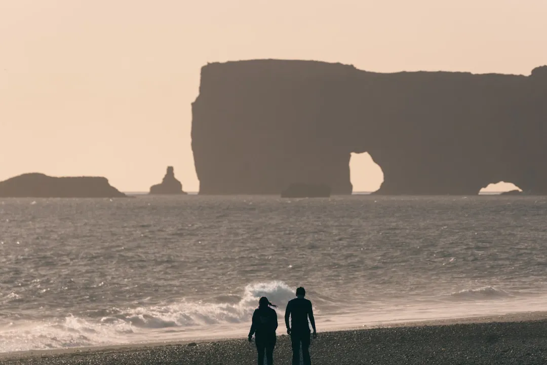 a couple of people standing on top of a beach