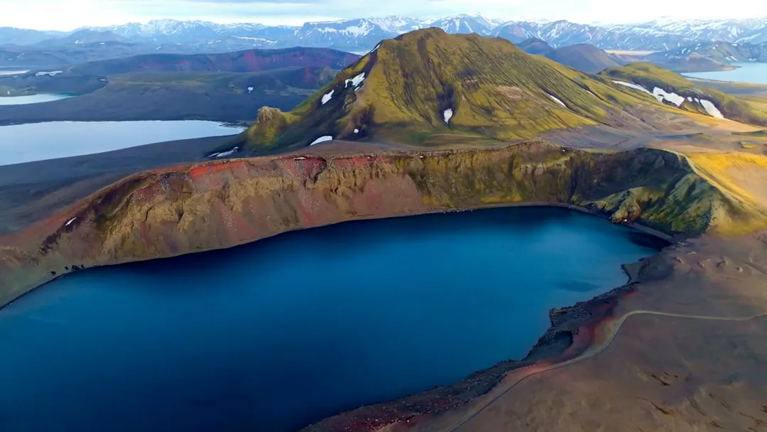 Vibrant blue lake surrounded by colorful, rugged volcanic hills
