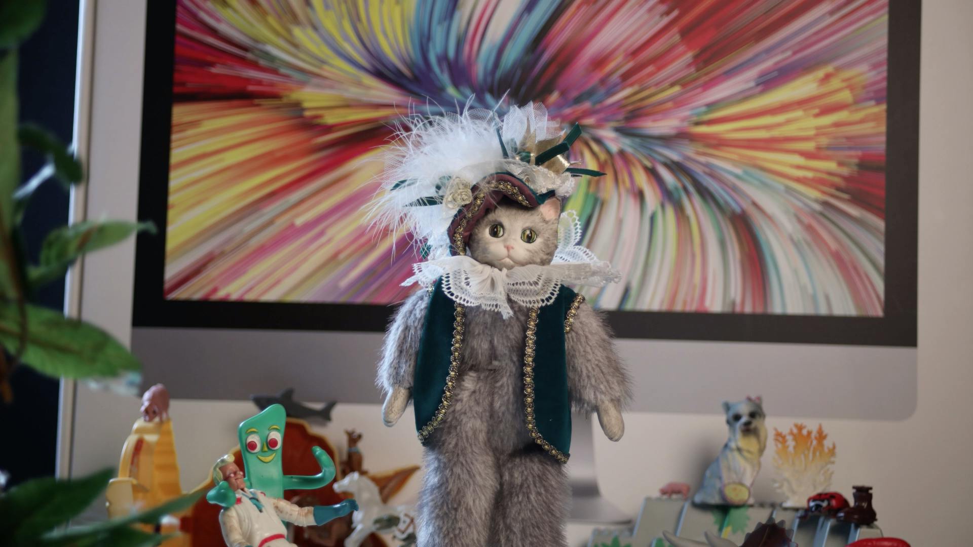 image of a plush cat in the middle of the frame, with various plastic figures around it
