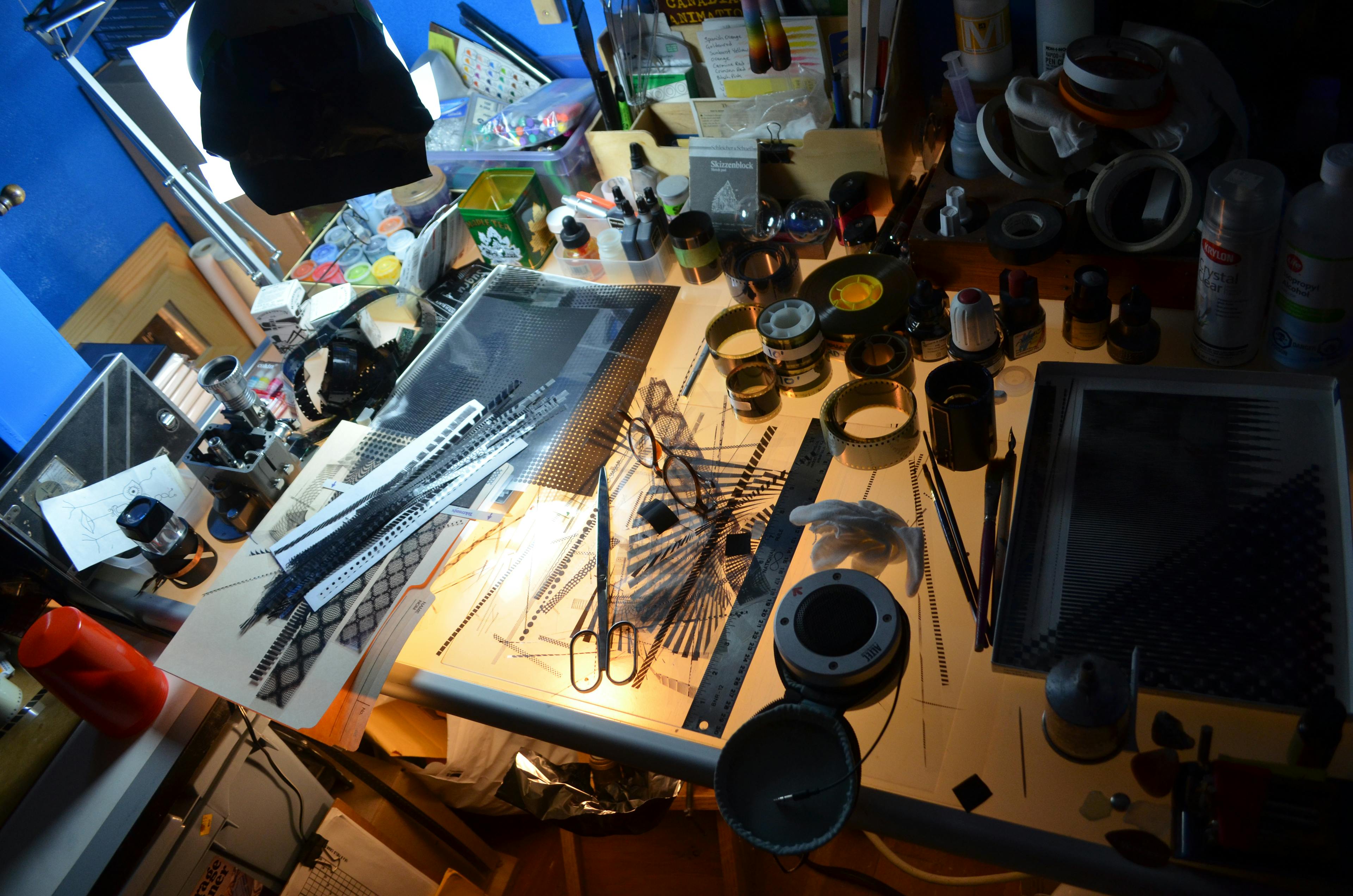 A table in Richard Reeves' studio, covered in analog film, scissors, rulers, and scratch-film tools