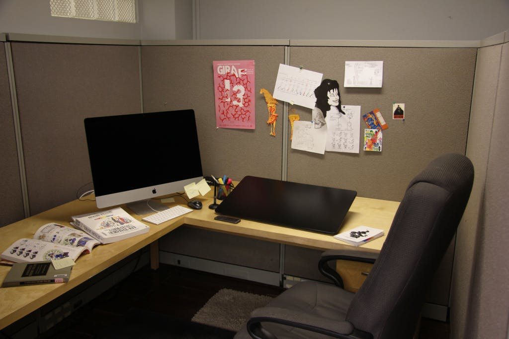 image of a hot desk studio in Quickdraw studios. Has an iMac, two open animation resource books, a Cintiq pro, and various assets pinned to the wall