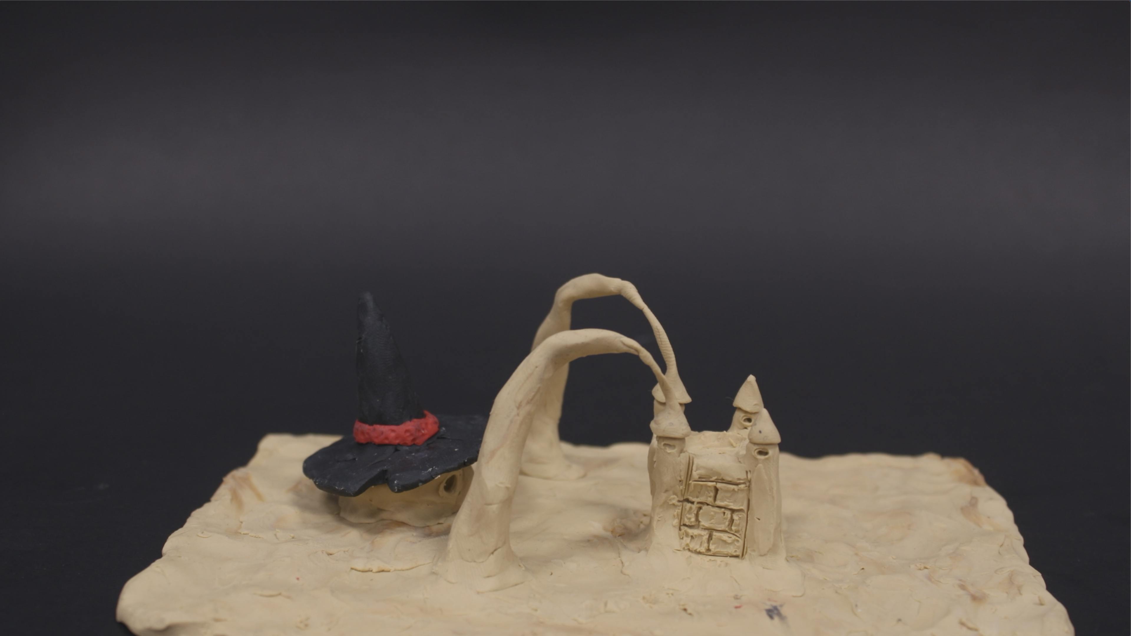 Clay sculpture of a "sand"witch about to break a sandcastle