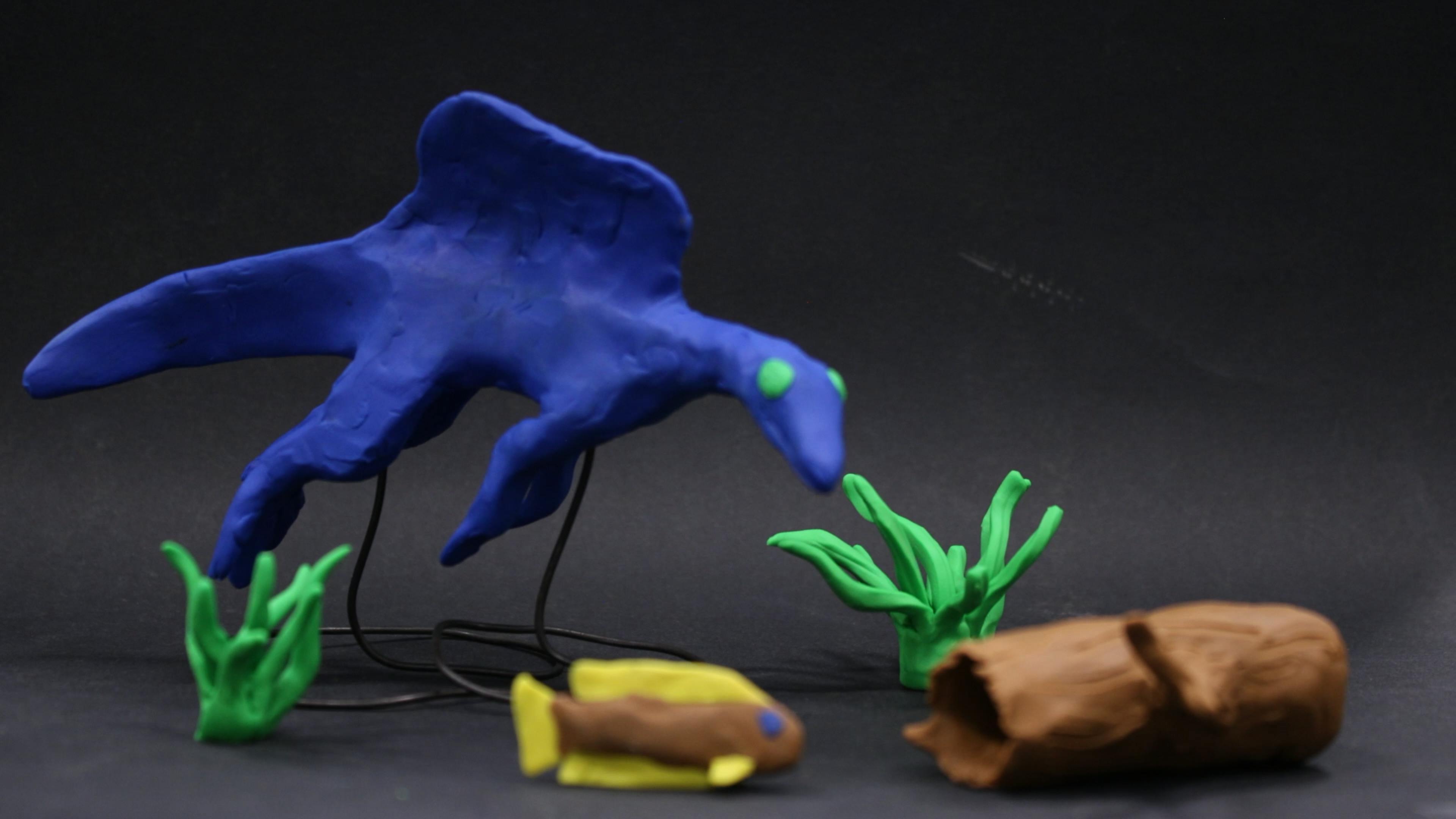 Claymation scene of a dinosaur swimming underwater and about to catch a fish