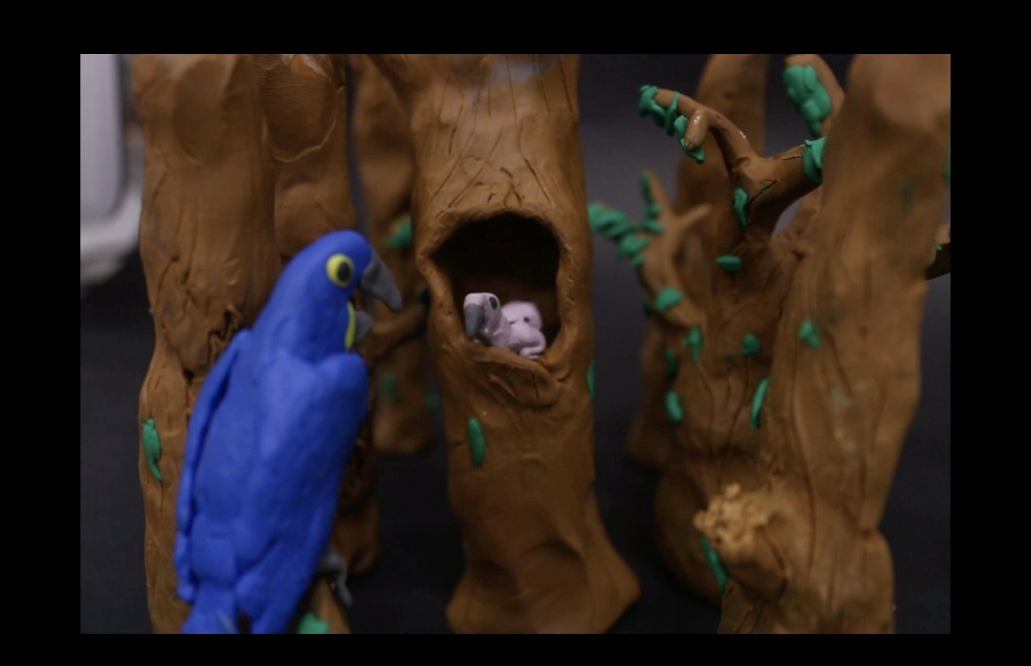 clay scene of a blue macaw parrot feeding her baby in a tree