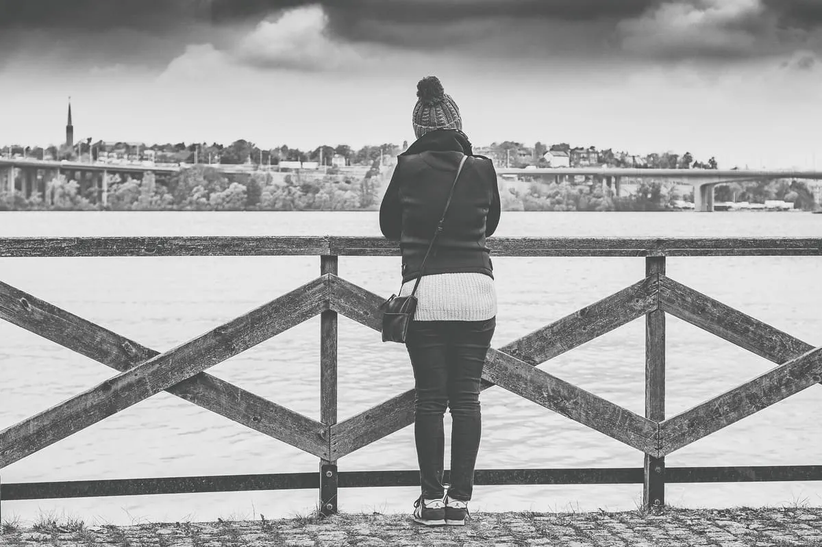 A woman leaning on a railing looking out over the water