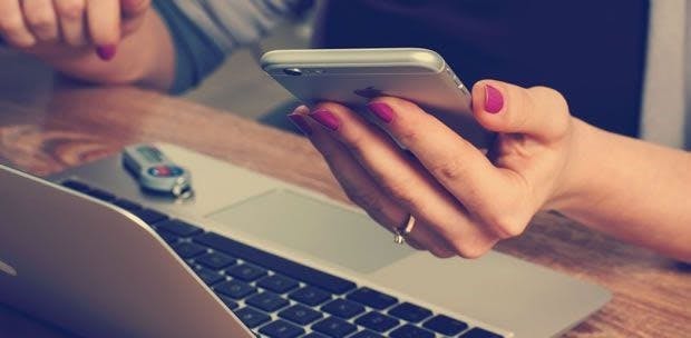 female holding an iphone 6 and a macbook pro 