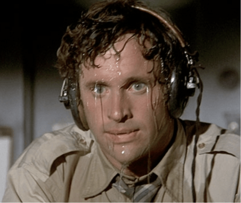 Military man, with curly hair, blue eyes, wearing headphones, that sweats