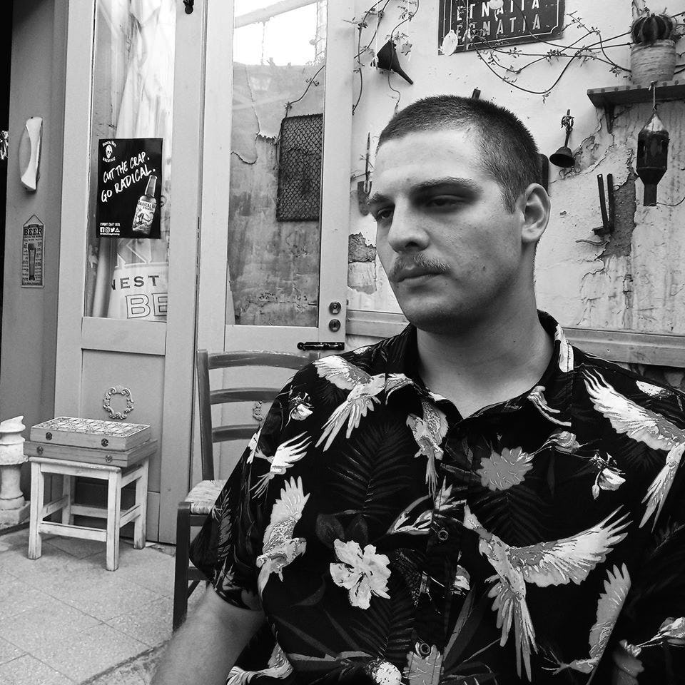 man looking skeptical, with flower shirt , with facial hair 