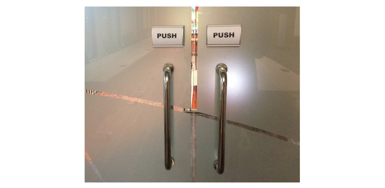 glass doors with signs on them "push"