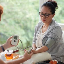 Female wearing glasses having blood pressure checks