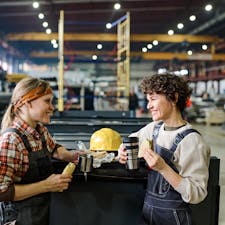 Two female workers eating their lunch on a break in a factory