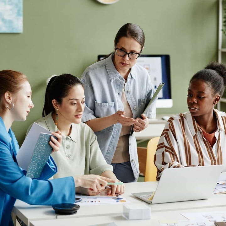 Team of female employees gathered around laptops