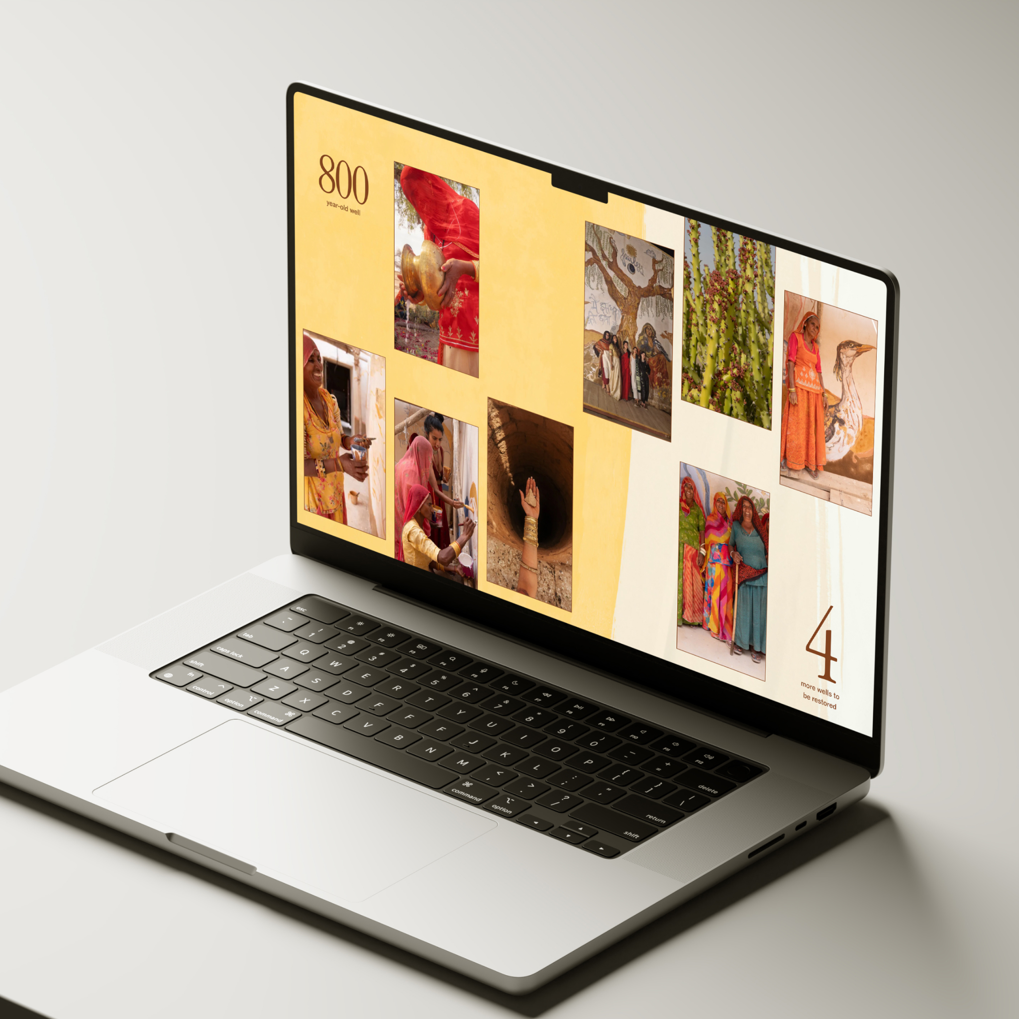 Laptop displaying a website with a warm yellow background showcasing a photo collage. The screen shows various images of women in colorful traditional clothing engaged in community activities, possibly related to water access projects. The page has '800' in the top corner and '4 more wells to be installed' at the bottom right, suggesting a development or charitable initiative tracking progress on water infrastructure projects.