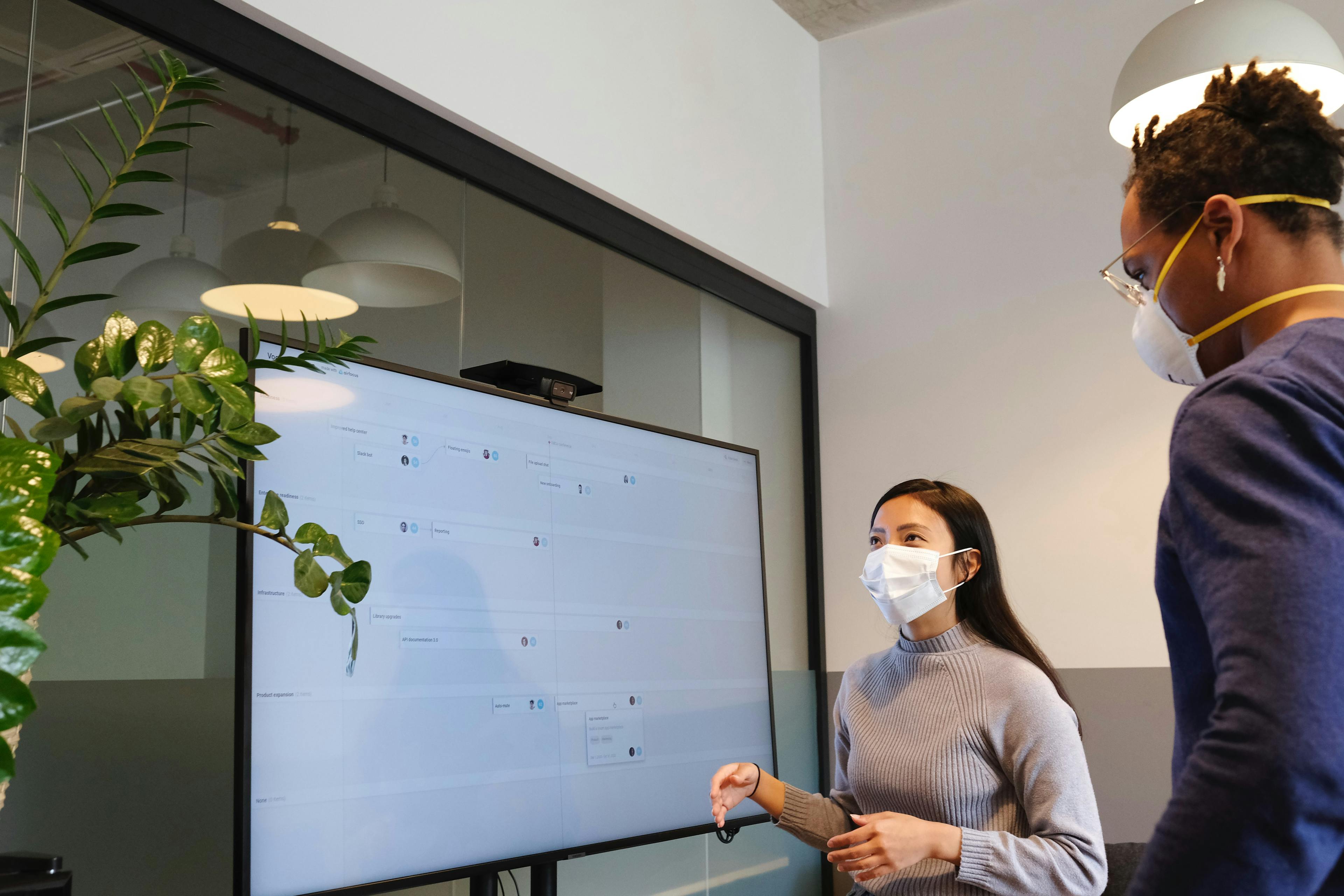 Two professionals working on a large monitor