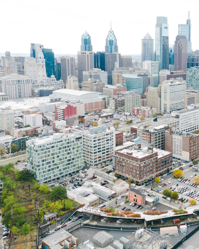 An aerial image of Phase One of the Rail Park and the undeveloped, overgrown Viaduct, with the Philadelphia skyline in the background