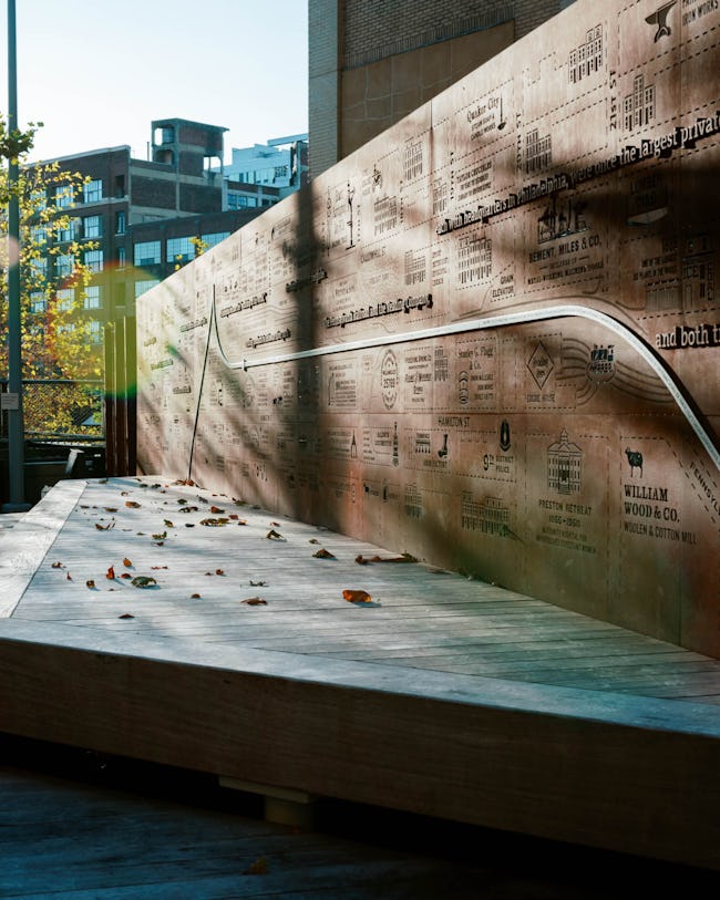 An image of the Story Wall at the Rail Park: an 80 foot galvanized steel wall that illustrates an 1895 atlas of Philadelphia with cutout icons of the businesses that were around the neighborhood at that time