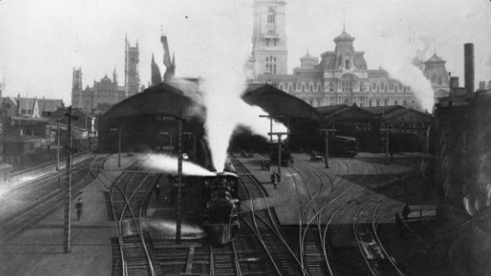 Black and white image showing a steam engine train leaving City Hall