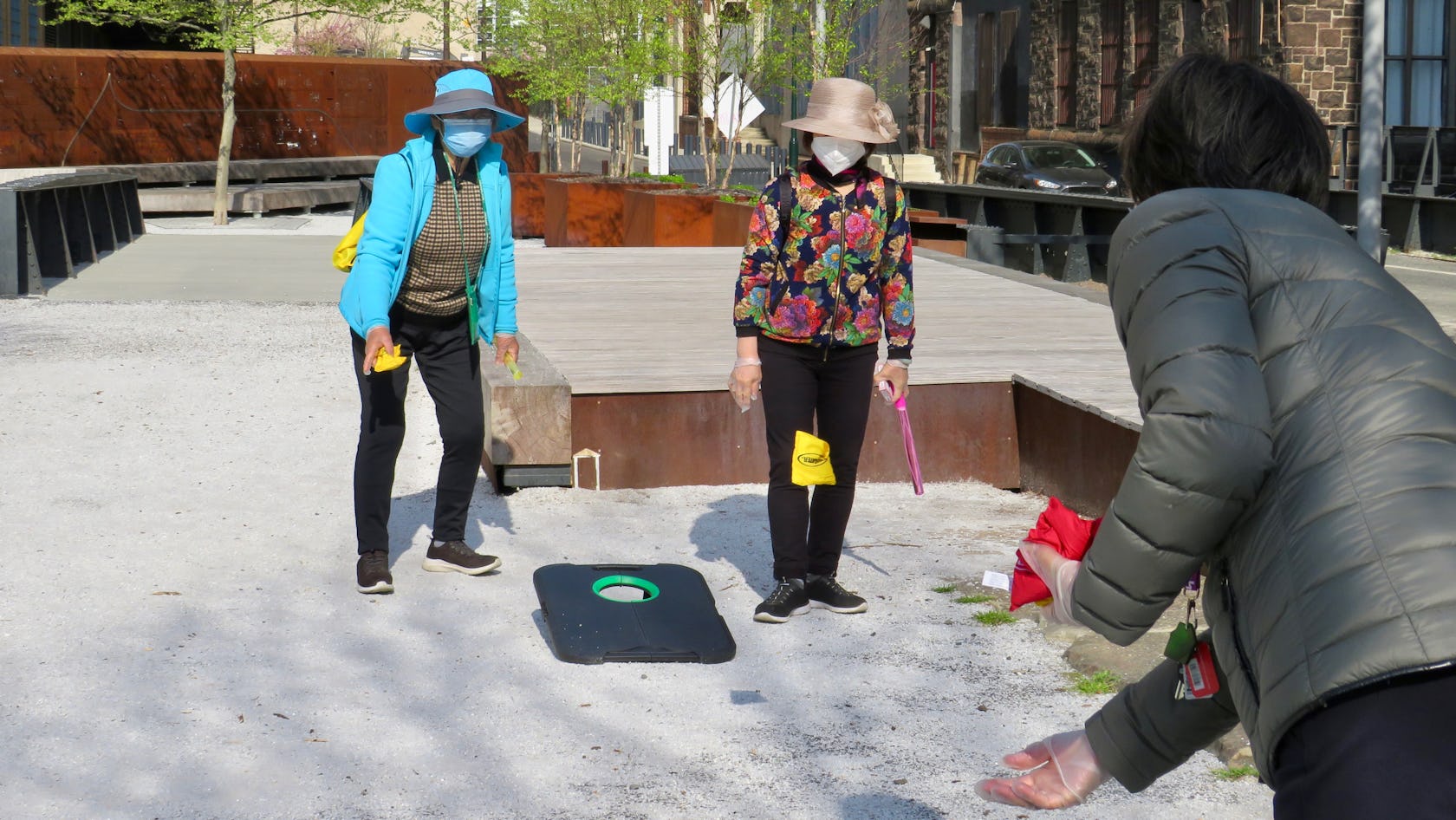 Three women play corn hole at Elder Hour - here they are tossing bean bags back and forth