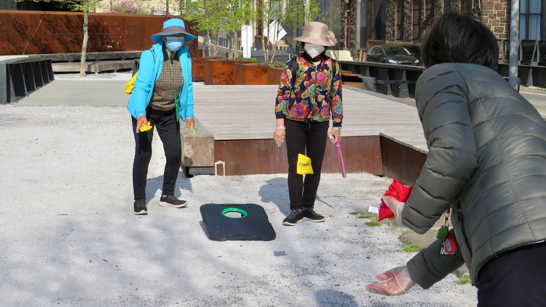 Three women play corn hole at Elder Hour - here they are tossing bean bags back and forth