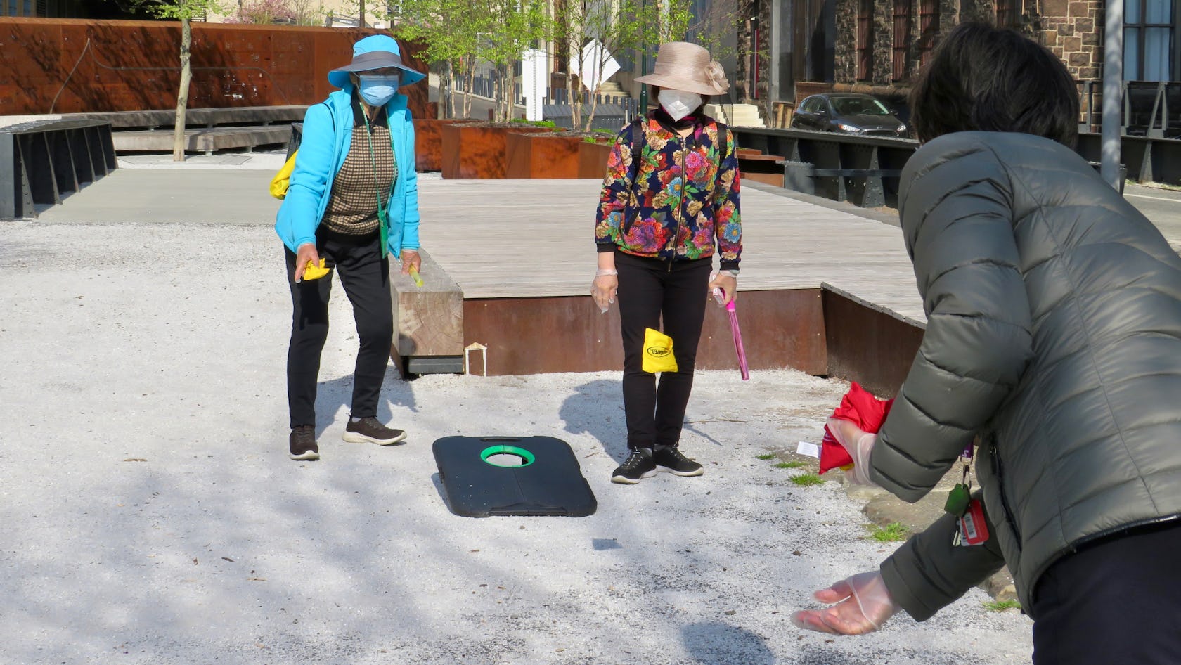 Three women play corn hole at Elder Hour - here they are tossing bean bags back and forth