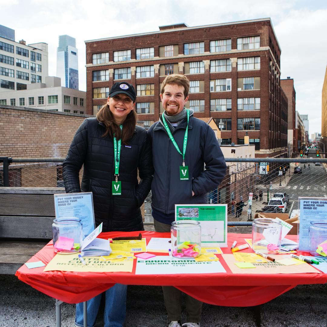 Two volunteers smiling in front of an activity table at an event at the Rail Park