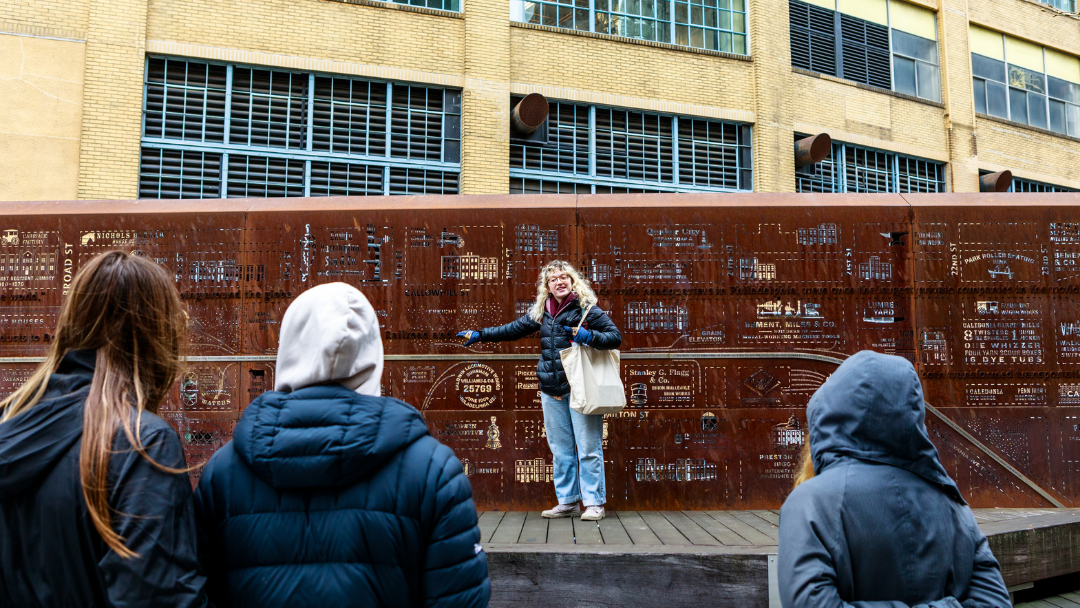 Tour Guide, Morgan, standing in front of the story wall