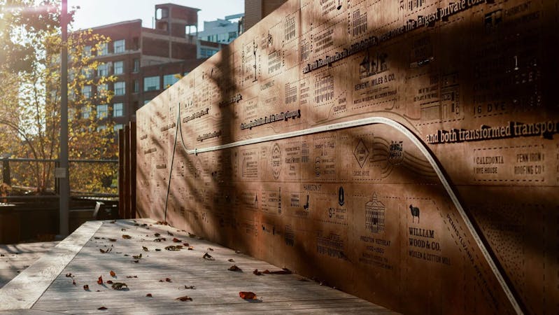 The Story Wall at the Rail Park, an 80 foot galvanized steel wall with laser cut imagery of a 1895 city atlas
