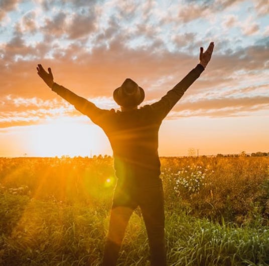 Man in field with arms raised