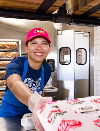 Crewmember serving up Chicken Finger meal