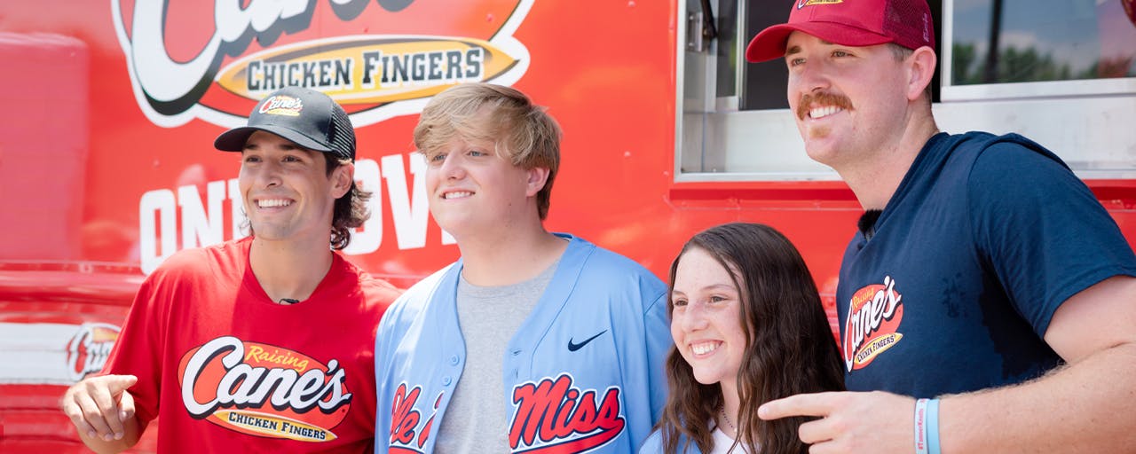 People posing in front of Raising Cane's food truck