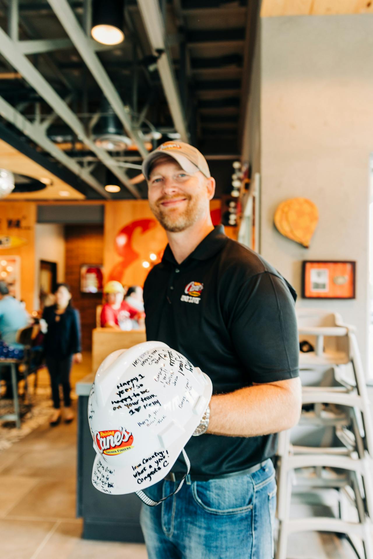 Crewmember holding a Raising Cane's hat