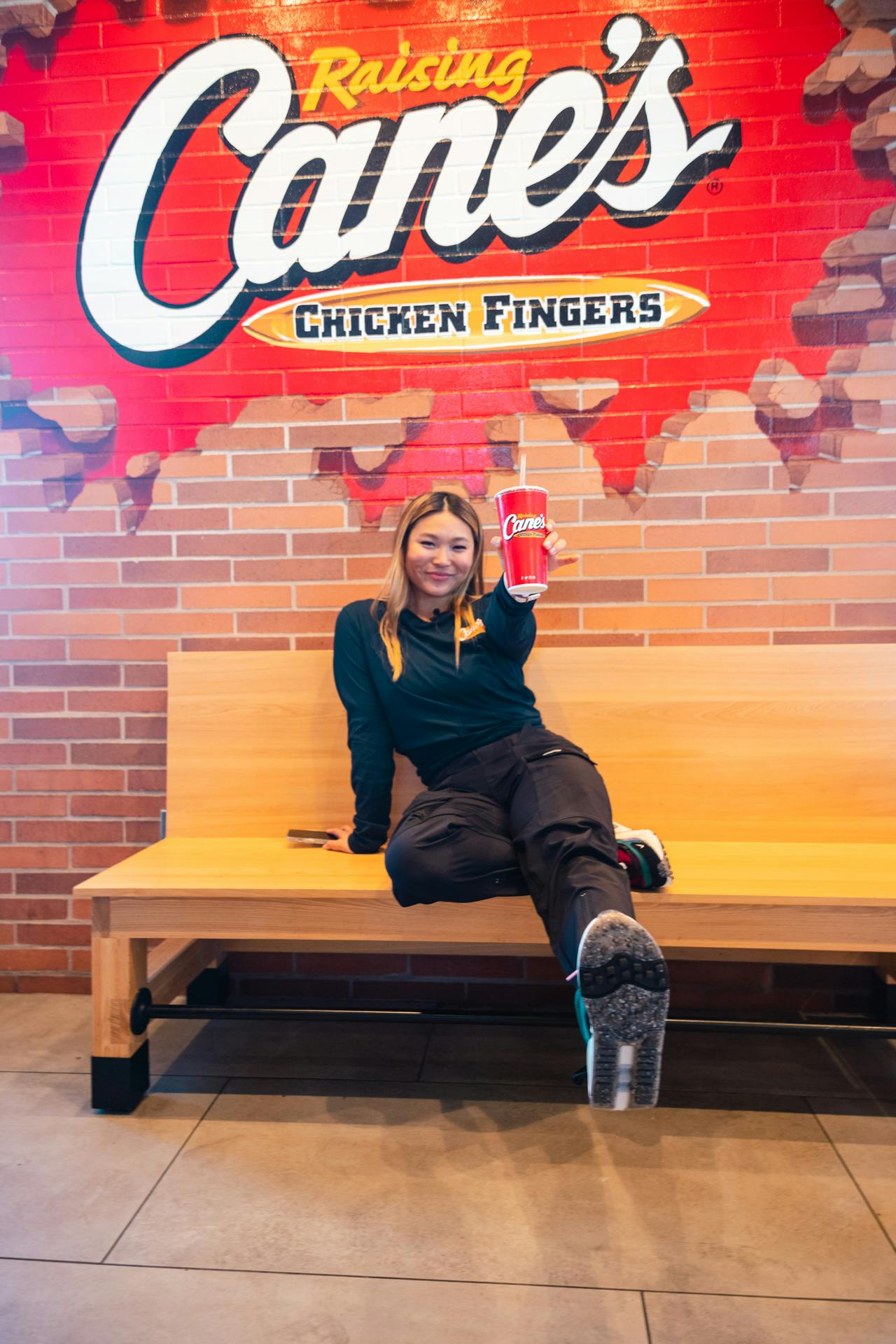 Chloe Kim sitting in front of a Raising Cane's mural