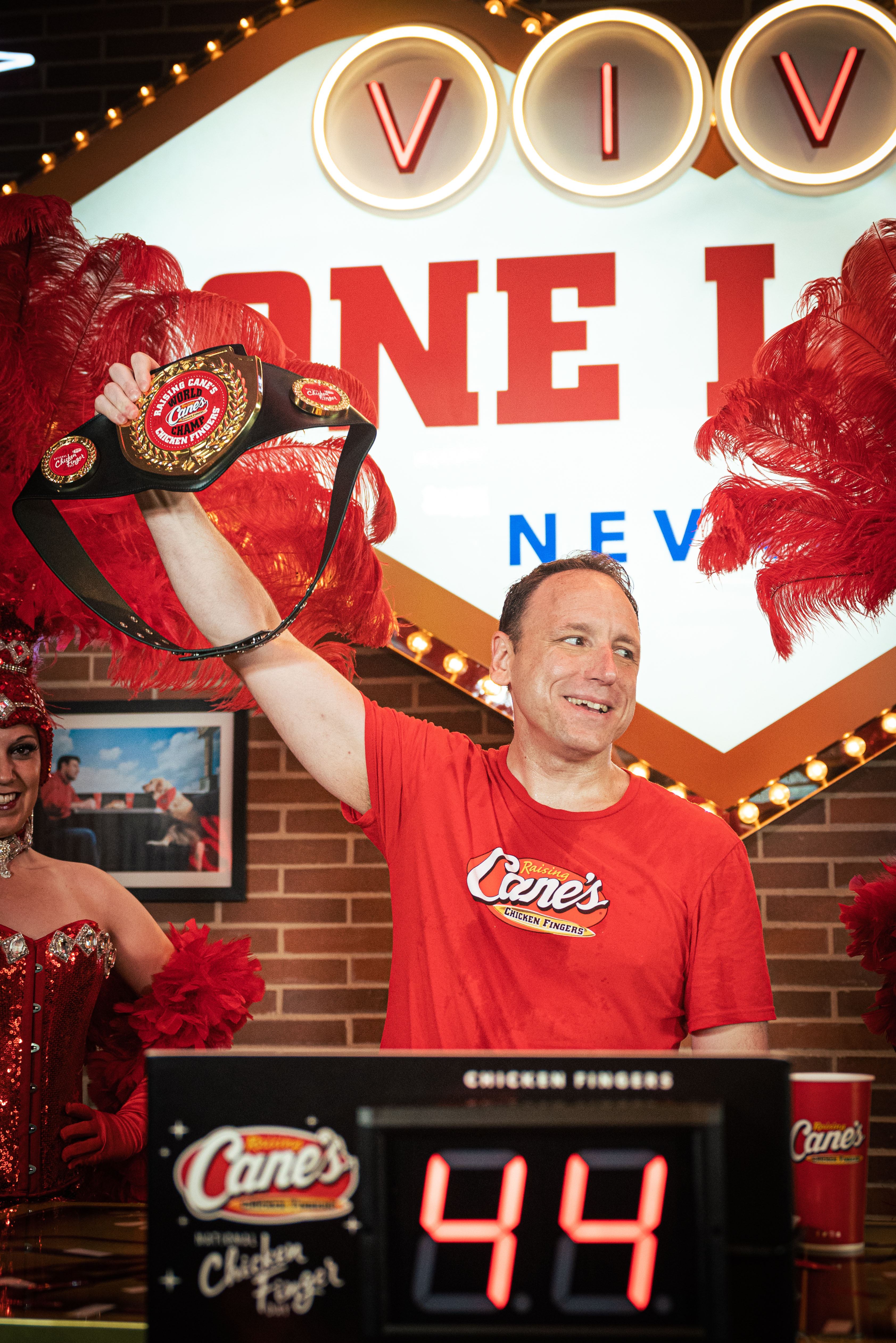 Joey Chestnut holding up Raising Cane's Chicken Fingers Championship belt