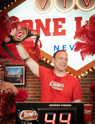 Joey Chestnut holding up Raising Cane's Chicken Fingers Championship belt