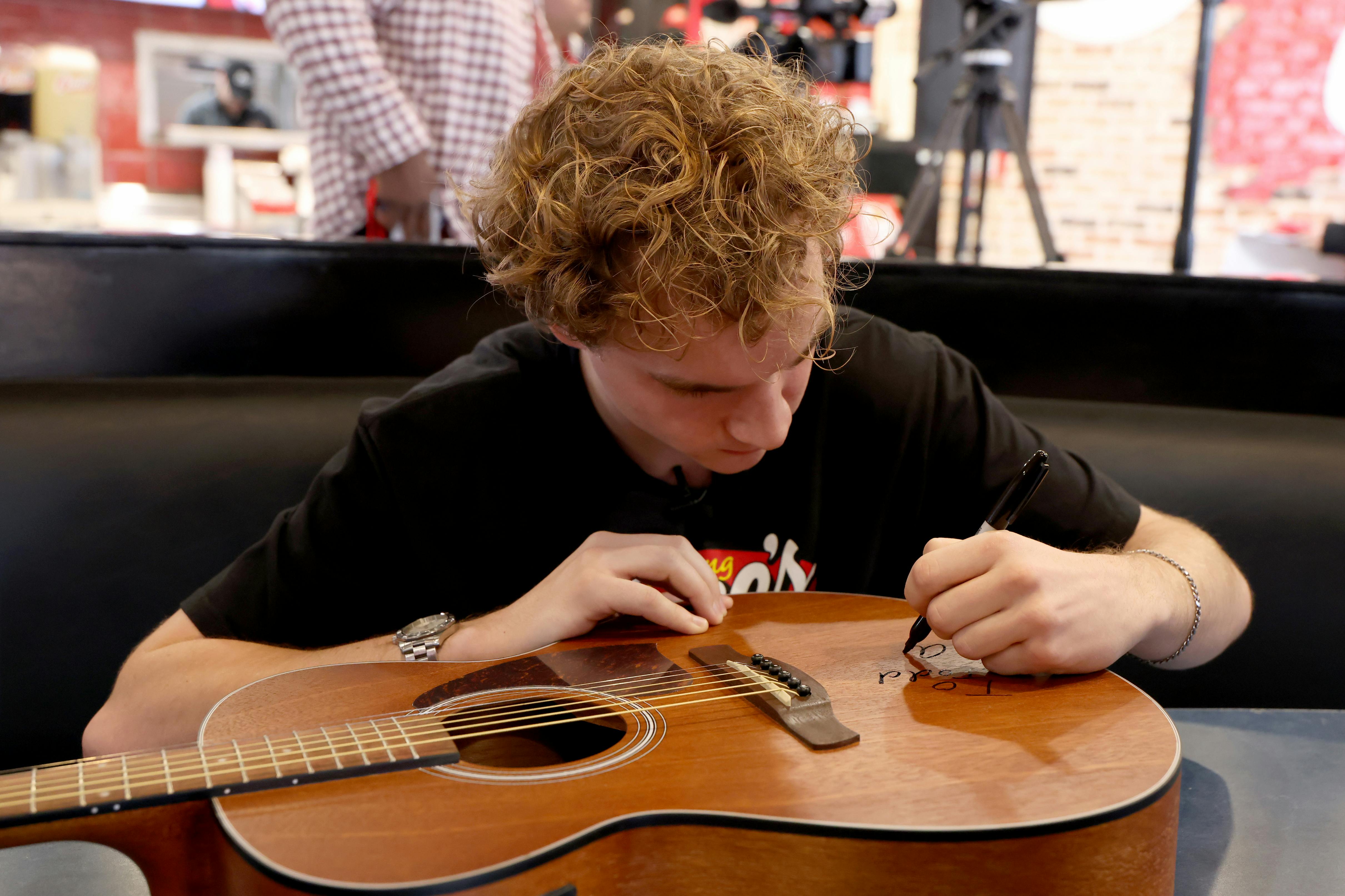 Aiden Ross signing a guitar at Raising Cane's