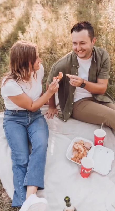 A couple taking engagement pictures with Raising Cane's.
