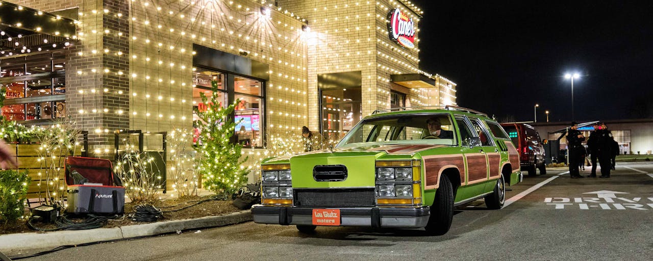 Griswold's station wagon in the drive-through of Raising Cane's decorated in holiday lights