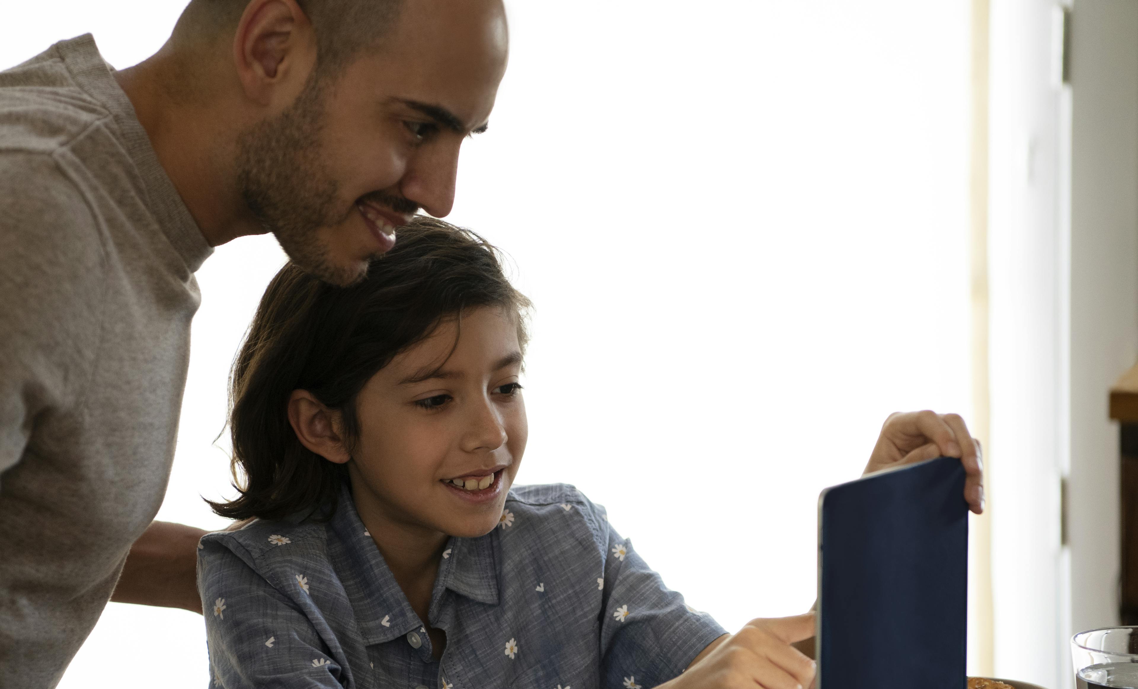 A boy and dad read together on an iPad