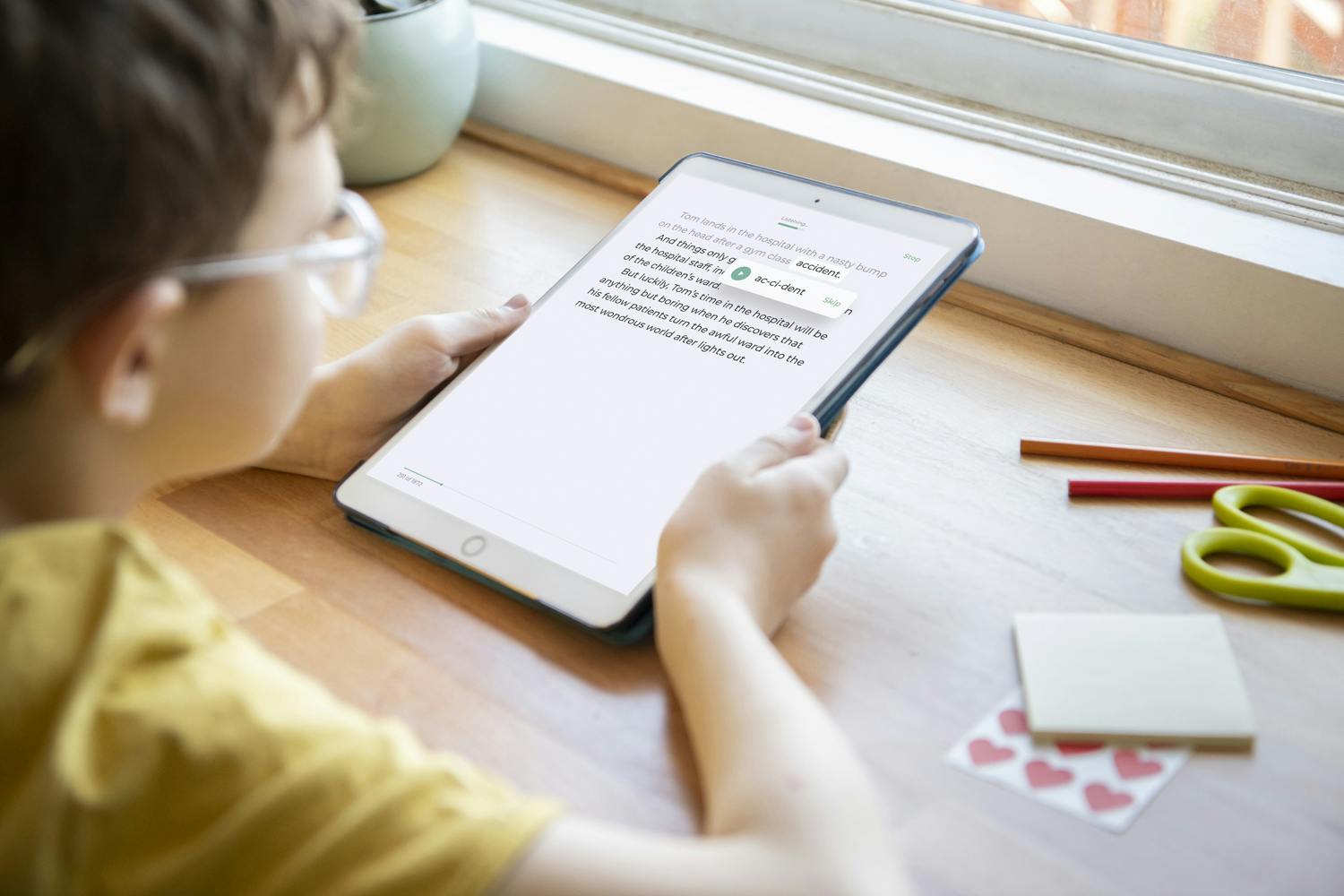 A child reads on an iPad at a desk