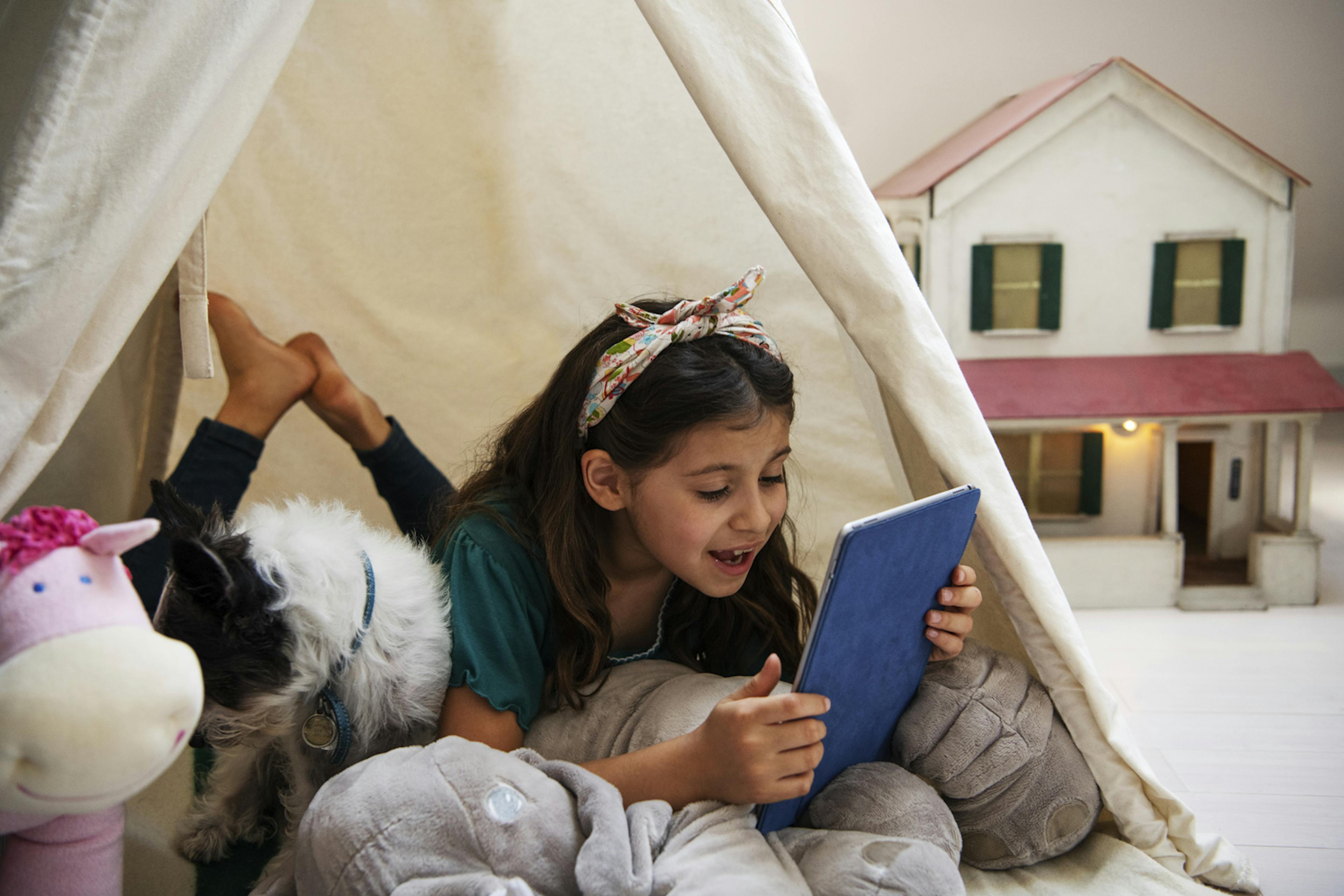 A chid reads in a cozy blanket fort