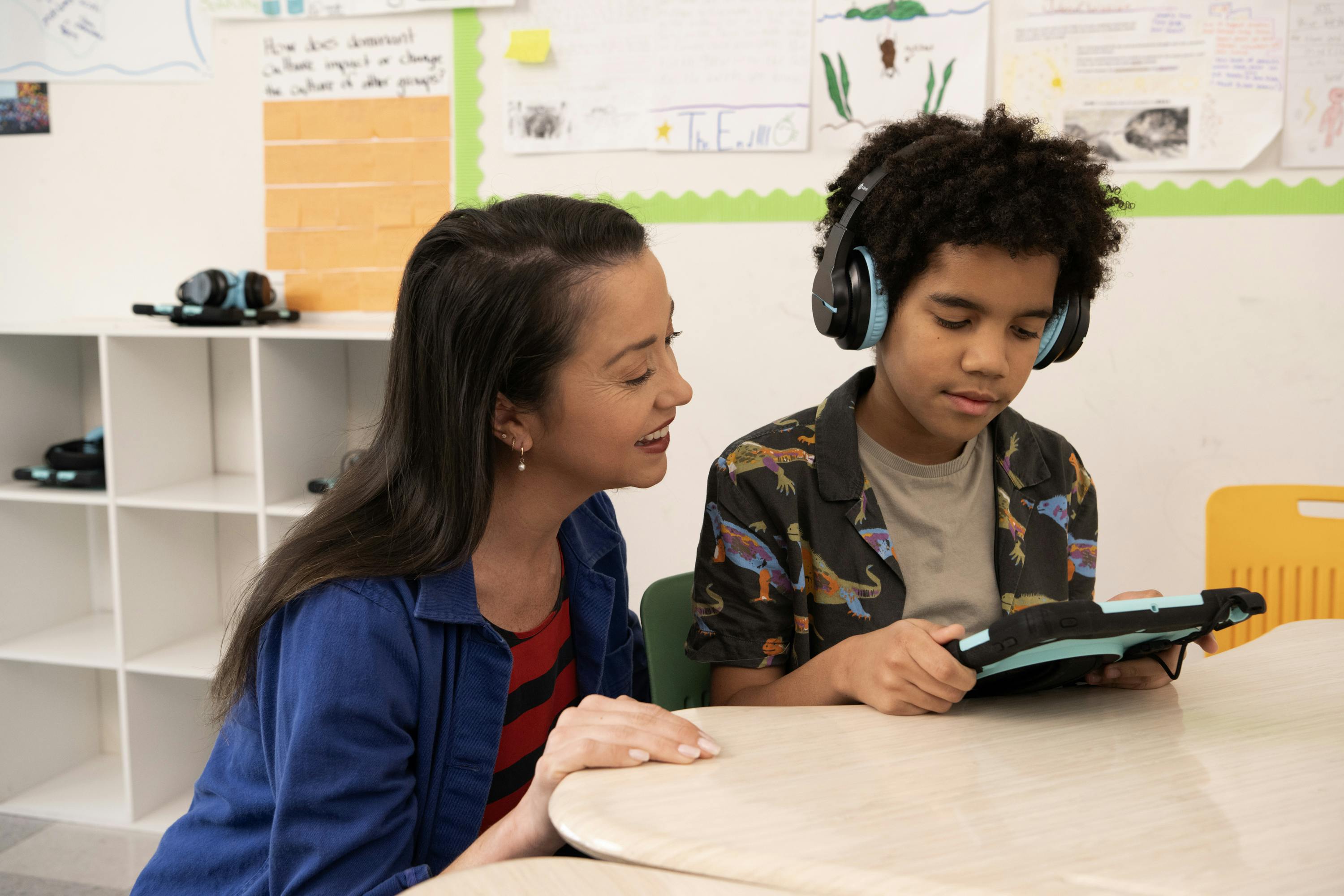 A teacher supports a student reading on an iPad