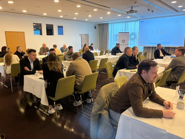 Fólk situr í sal og talar saman