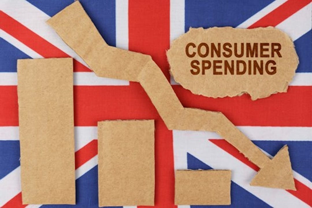 Photo of graph with arrow pointing down and a Union Jack flag in the background
