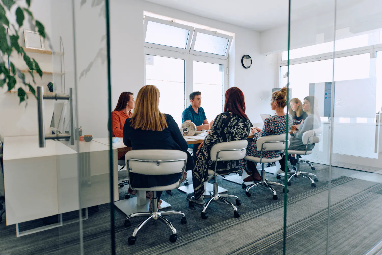 Photo showing a calibration meeting taking place. A group of managers sits around a meeting table, in a meeting room with glass windows.