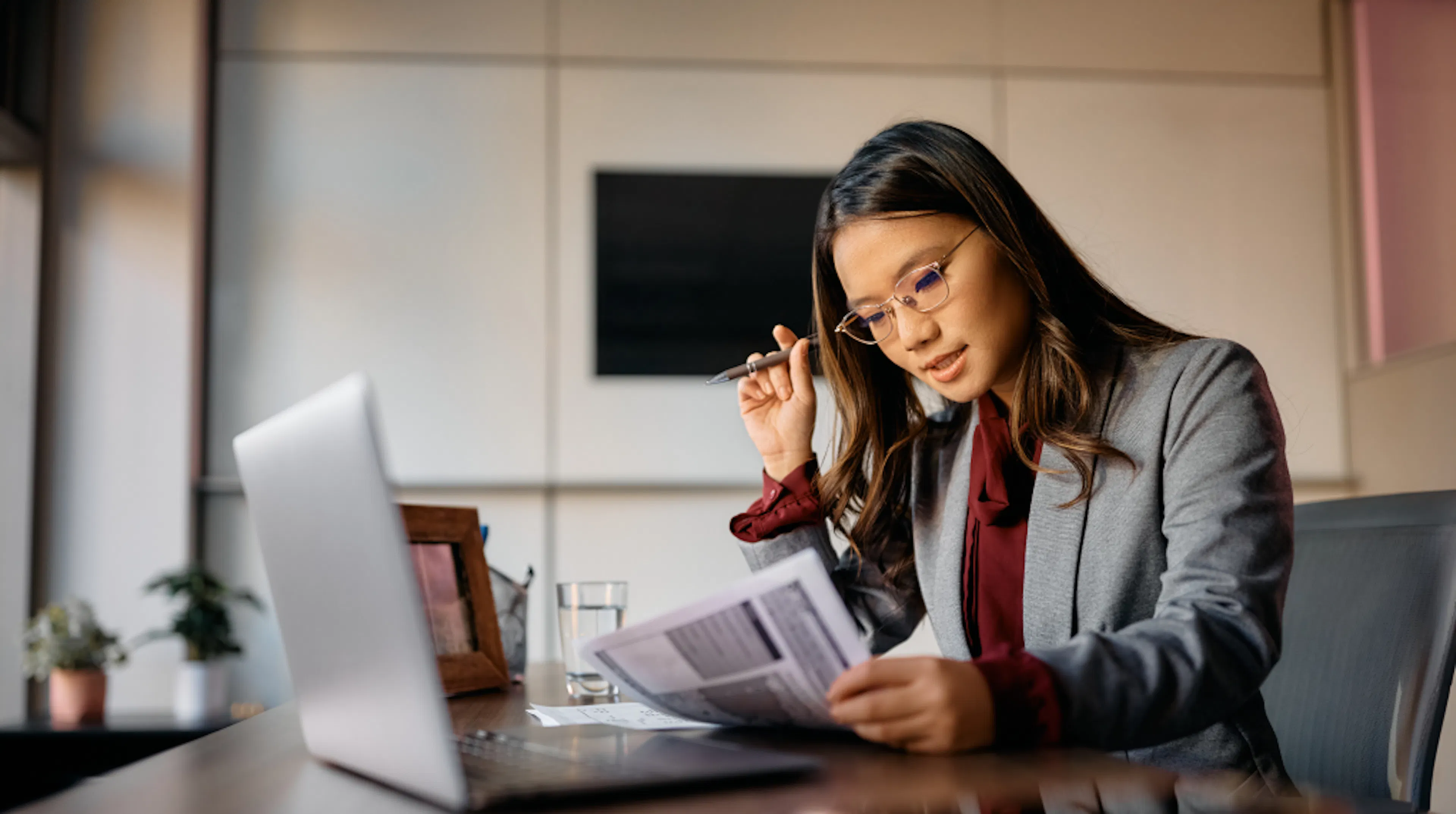 Photo of an Asian woman in an office working at her laptop. 